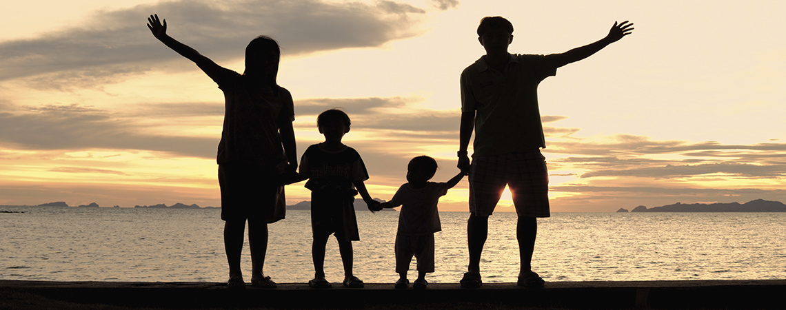 silhouette of family on the beach at dusk.