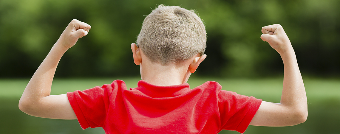Young boy raising his hands in the air and celebrating success or victory.